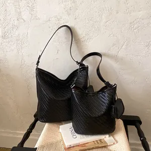 Close-up detail of black woven leather shoulder bag and bucket bag set in a lifestyle scene