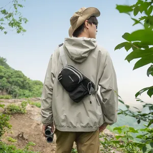 Man wearing a black multi-functional outdoor crossbody bag in a mountain setting