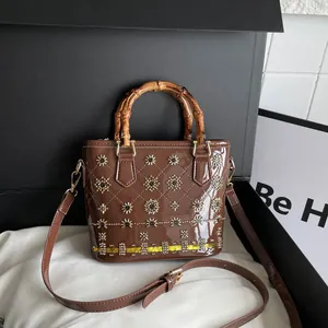 Brown patent leather shoulder bag featuring a vintage bamboo handle and gold flower details