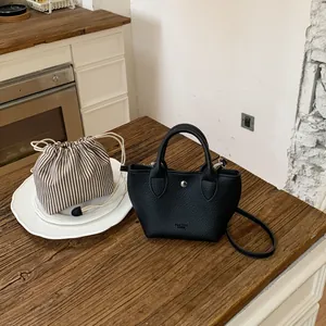 Mini sac à main en cuir noir avec pochette rayée sur une table en bois massif