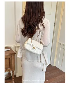 Detailopname van een vrouw die een witte gewatteerde ketting-crossbodytas draagt