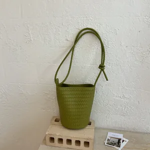 Hochwertige grüne gewebte Beuteltasche auf einem minimalistischen Steinständer-Hintergrund