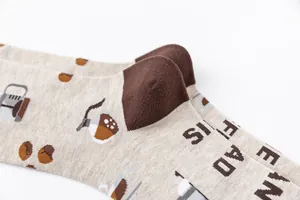 Close-up of coffee-themed crew socks showing knitted bean patterns and soft cotton texture.