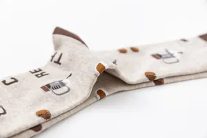 Close-up macro detail of beige cotton socks with coffee bean and French press patterns.