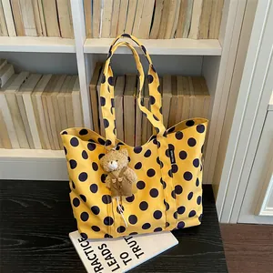 Detail of yellow polka dot tote bag with a cute bear charm in a library setting