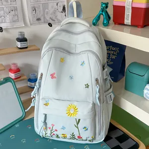Zaino estetico celeste con ricamo floreale in un accogliente ambiente di studio