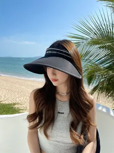 Vue détaillée d'une visière pare-soleil noire à large bord pour femme à la plage.