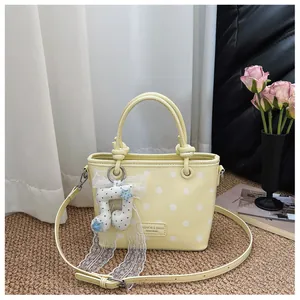 Stylish light yellow polka dot handbag featuring a decorative musical note lace charm