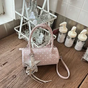 Close-up of a pink polka dot cylinder handbag featuring a stylish star and horse charm