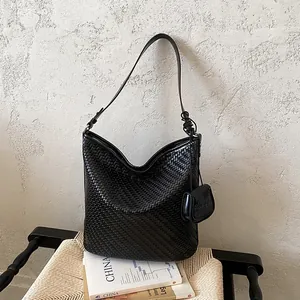 Large black woven shoulder bag with elegant texture and decorative pouch charm detail