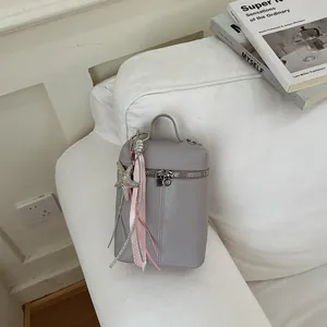 Dettaglio mini borsa a tracolla grigia con ciondolo a stella e nastri su divano.