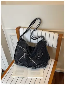 Vue détaillée du sac bandoulière en denim noir vintage avec fermetures éclair style motard.