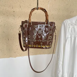 Detailed view of brown patent leather bucket bag featuring unique bamboo handles.