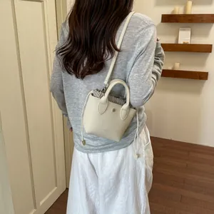 Vue de dos d'une femme portant un mini sac seau crème avec cordon de serrage rayé