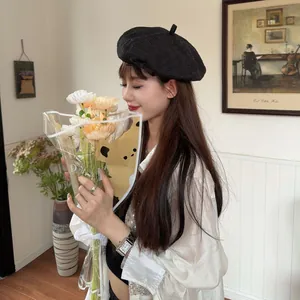 Fashionable Asian model wearing a chic retro black beret hat in a cozy indoor room setting