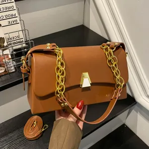 Detail shot of stylish brown shoulder bag with a gold chain strap and metal lock clasp