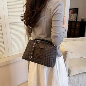 Detailansicht der braun gewebten Handtasche mit dem Kronenlogo und Silbernieten
