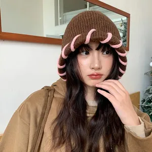 Asiatische Frau mit gemütlicher brauner Strickmütze und rosa Rand für den Winter
