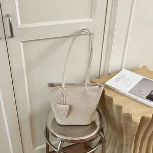 Gedetailleerd overzicht van een crème geweven draagtas met een elegante schouderband