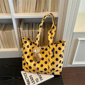 Detailed view of yellow polka dot tote bag with a cute teddy bear charm accessory