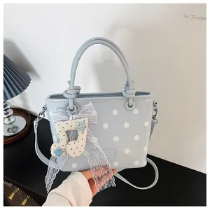 Detailed view of the musical note charm and lace ribbon on a light blue polka dot bag