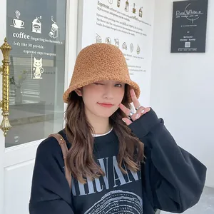 Stylish fuzzy brown lamb wool bucket hat for women shown in a cozy cafe lifestyle setting
