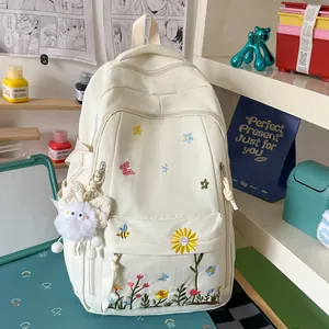 Dettaglio di uno zaino beige in stile giapponese con ricami floreali e ciondolo di peluche