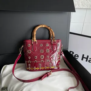 Vintage burgundy patent leather handbag with iconic bamboo handle and elegant floral studs