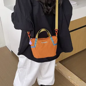 Back view of a woman wearing an orange nylon crossbody bag with blue details