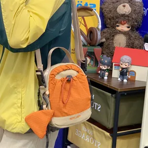 Détail d'un petit sac à bandoulière orange avec cordon de serrage et motif quadrillé