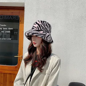 Détail d'un bob en peluche à motif zébré sur un mannequin devant un mur blanc chic