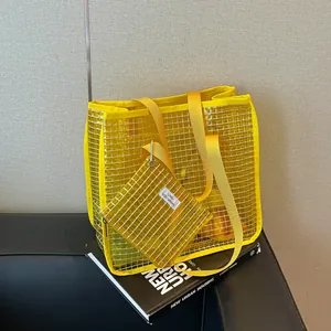Modern yellow mesh tote bag and matching pouch set on architectural book background.