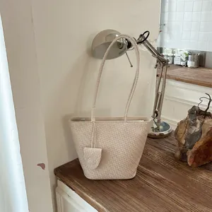 Close-up van een minimalistische crème geweven draagtas op een rustiek houten bureau
