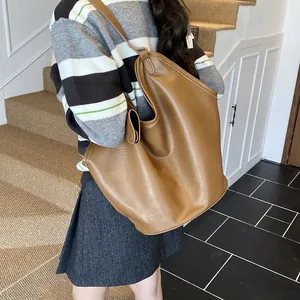 Back view detail showing a large brown leather hobo bag on a model in casual outfit
