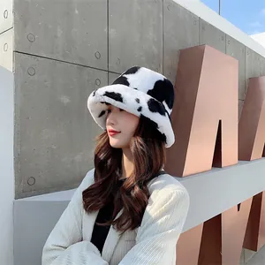 Side profile detail of a plush cow-print bucket hat worn by a model in urban setting
