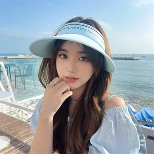 Femme portant un chapeau visière bleu clair à large bord sur une plage ensoleillée
