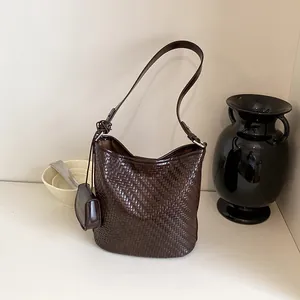 Detailed macro view of high-quality woven texture on a dark brown shoulder hobo bag