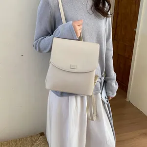 Detailed side view of a minimalist beige faux leather backpack on a model in grey knit