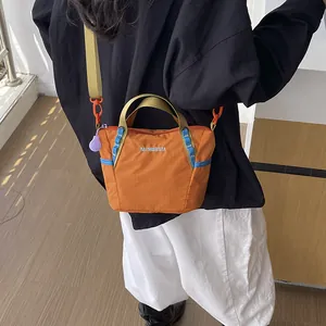 Detailed view of a trendy orange crossbody yoga bag with contrast light blue trim and handles.