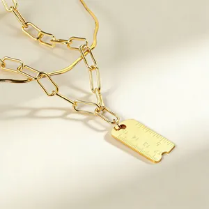 Vue détaillée d'un pendentif règle en acier inoxydable doré sur une chaîne à maillons