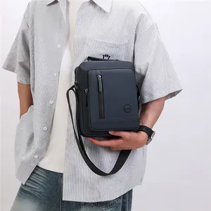 Detailed shot of a navy blue nylon crossbody messenger bag worn by a casual male model