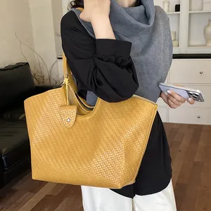 Stylish large yellow woven tote bag on model featuring an intricate textured pattern