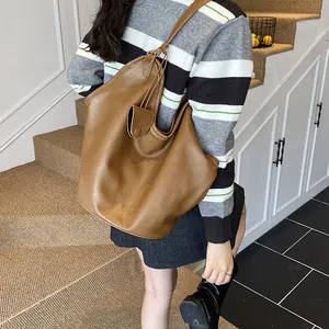 Rear view of large capacity brown hobo shoulder bag worn on shoulder in casual indoor setting