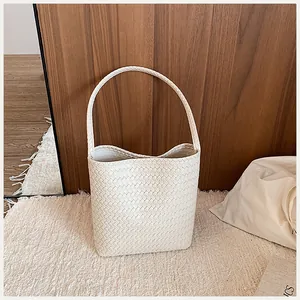 Primer plano de un bolso de cubo trenzado blanco con un diseño minimalista elegante.