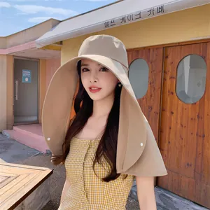 Asiatisches Model trägt einen beigen Sonnenhut mit breiter Krempe und Nackenschutz im Café