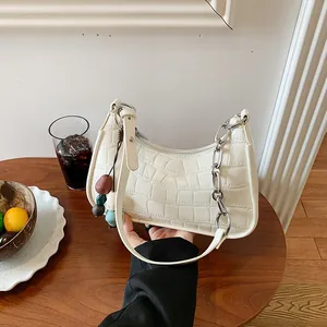 Elegant white crocodile pattern dumpling handbag with silver chain held in hand