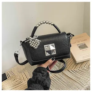 Detail of black crinkled leather handbag with silver beaded handle and heart charm.