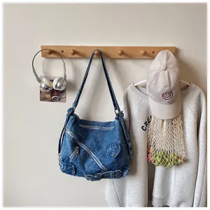 Sac à bandoulière en jean bleu vintage suspendu à un support en bois avec accessoires