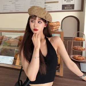 Stylish retro frayed beret hat in khaki worn by a model in a cozy cafe setting