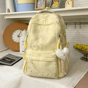 Detail of pastel yellow large capacity backpack with heart patterns and plush heart keychain